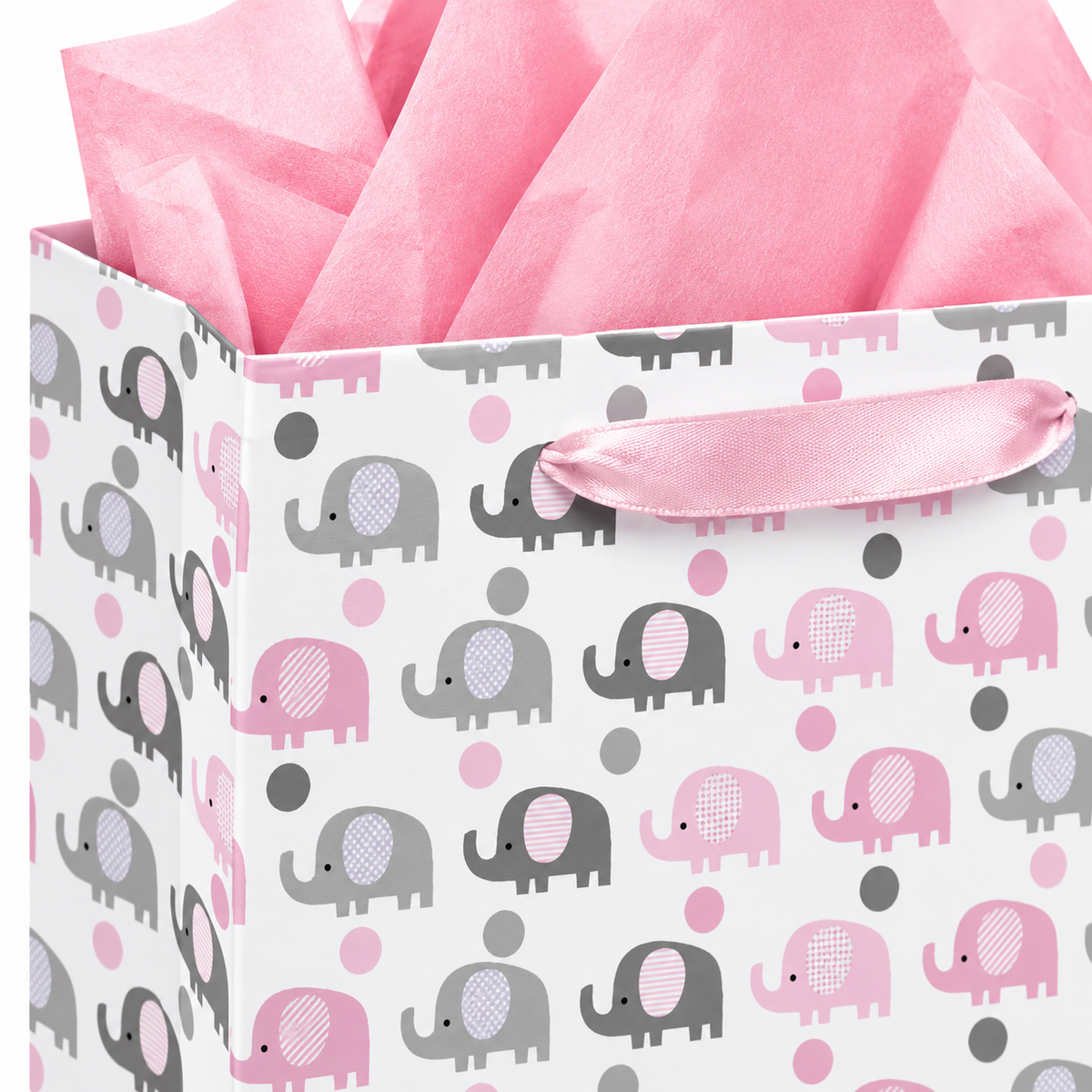 Close-up of pink satin ribbon handle, elephant print, folded paper corner and pink tissue