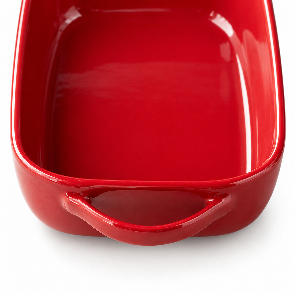 Close-up of the red ceramic dish's open loop handle and glazed rim