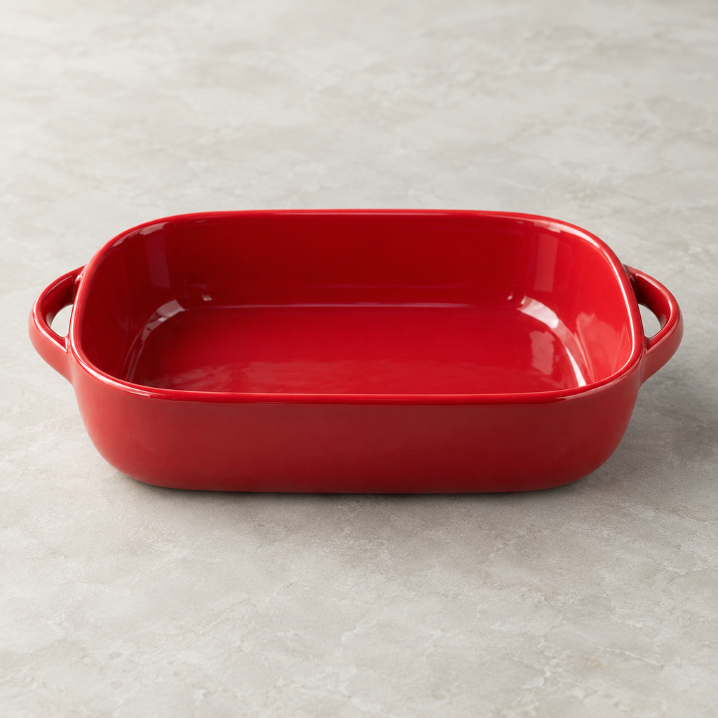 Red compact rounded-rectangular ceramic dish, empty low side view showing deep walls and two loop handles