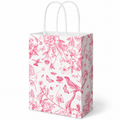 Whaline white gift bag with pink bird and floral print: white studio view; background objects are styling props